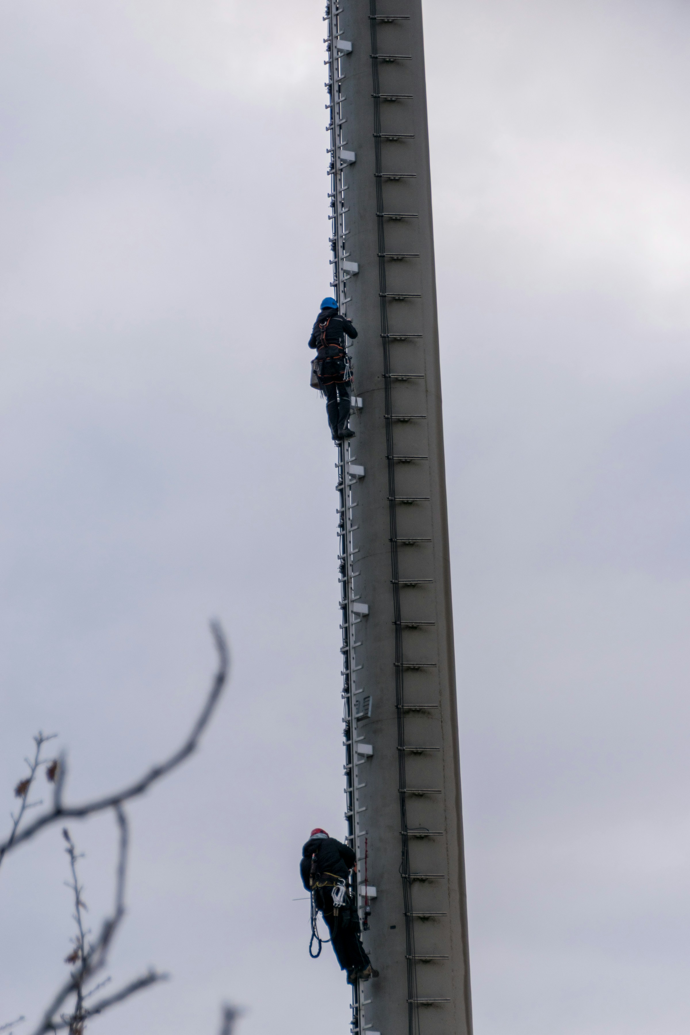Technician installing a light fixture at height on a steel tower